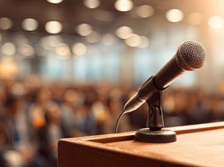 Microphone stands ready at a podium on stage before a blurred audience