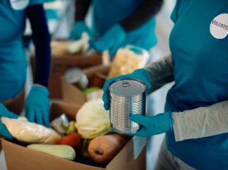 Unrecognizable volunteers packing donated food in cardboard boxe unrecognizable volunteers packing donated food inside cardboard boxes
